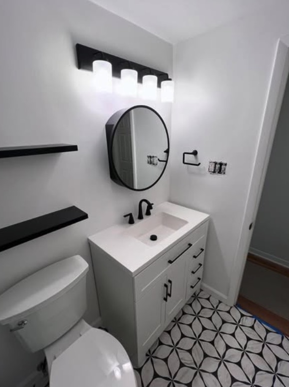 Bathroom remodel with white vanity and round black mirror