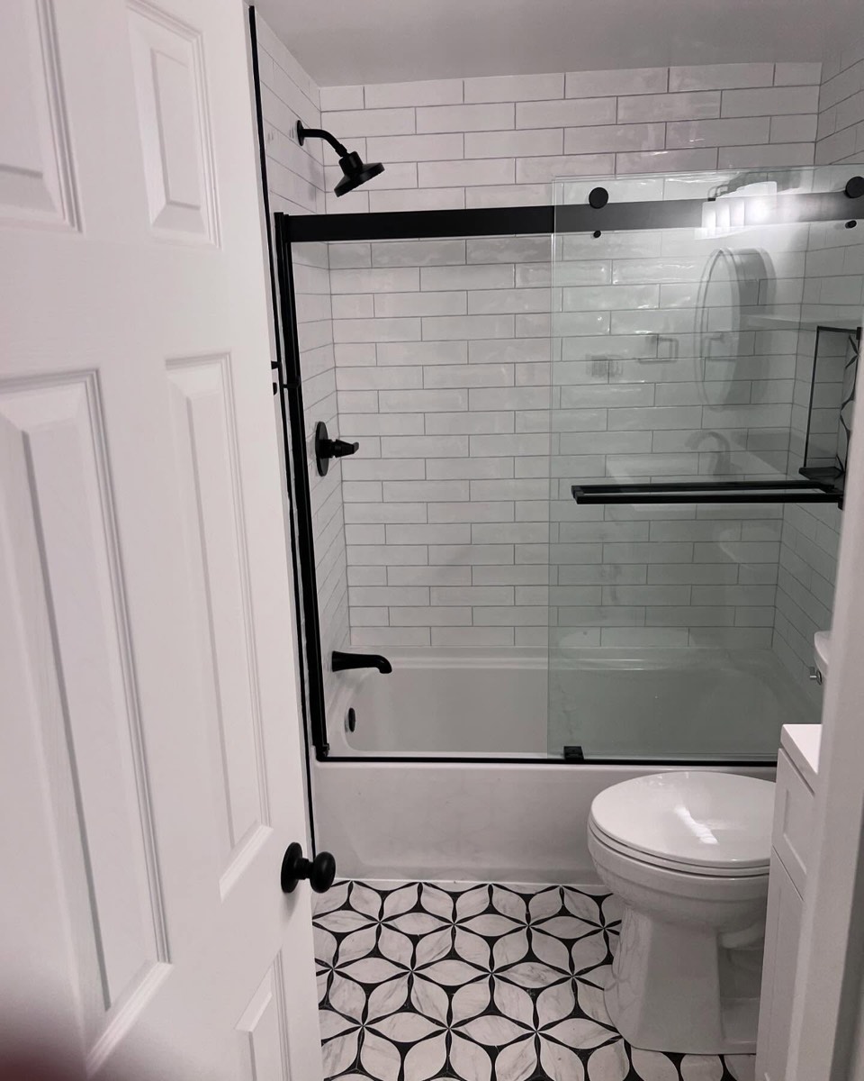 Bathroom remodel with black-and-white patterned floor tile, subway-tile tub surround, and black fixtures