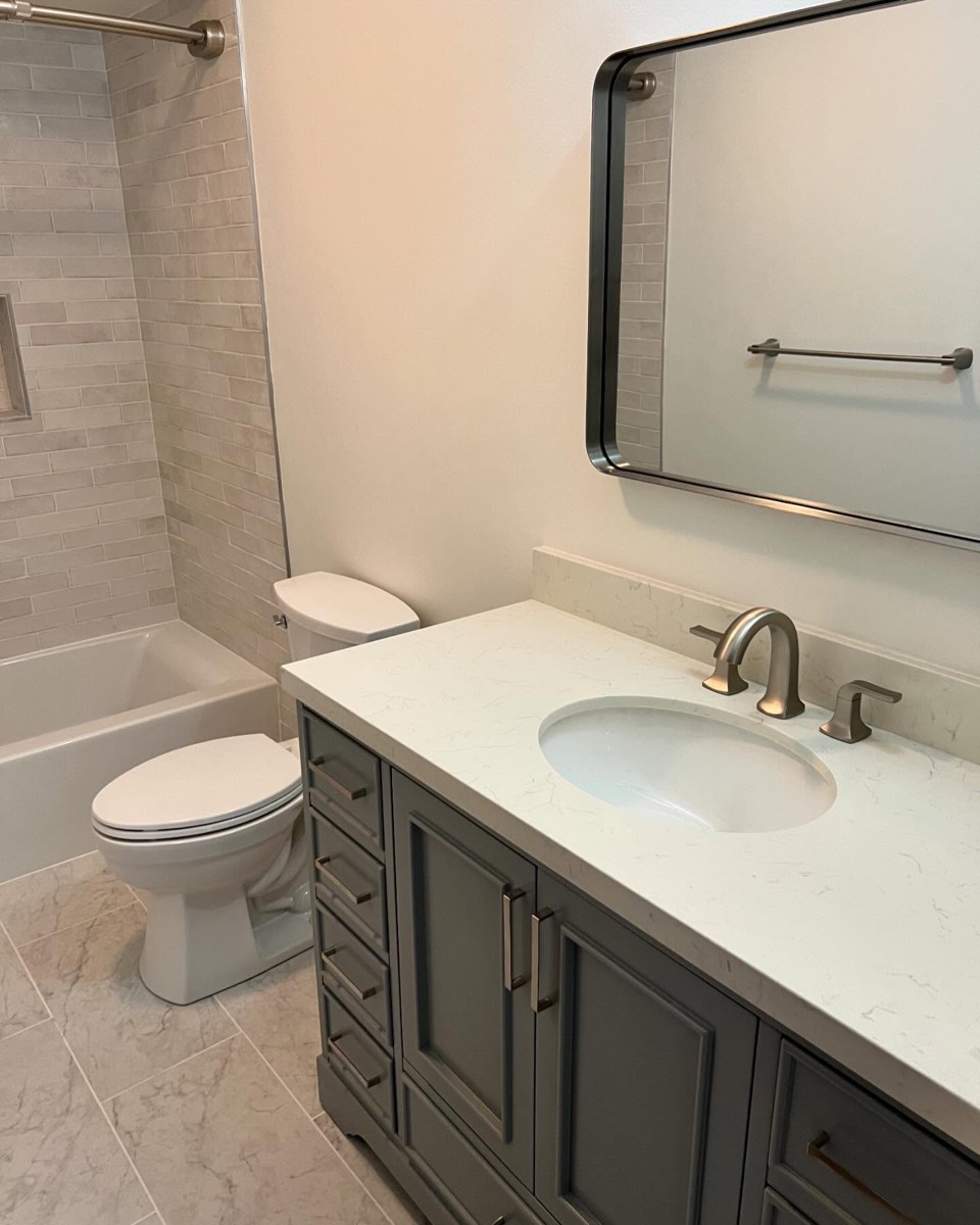 Bathroom with glazed Spanish wall tile, marble-top vanity, and framed mirror