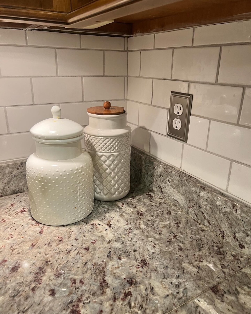 Kitchen with white subway-tile backsplash and speckled granite countertop