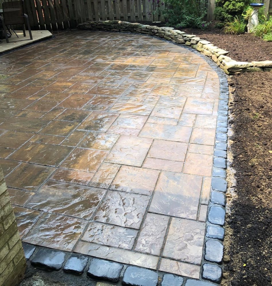 Unilock Beacon Hill paver patio with court-stone border and natural stone garden wall