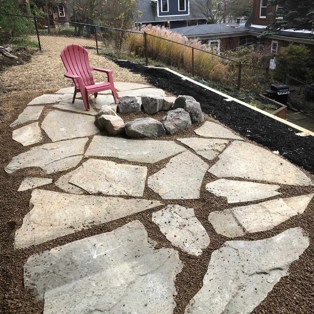 Flagstone sitting area with natural stone fire pit on a hillside yard