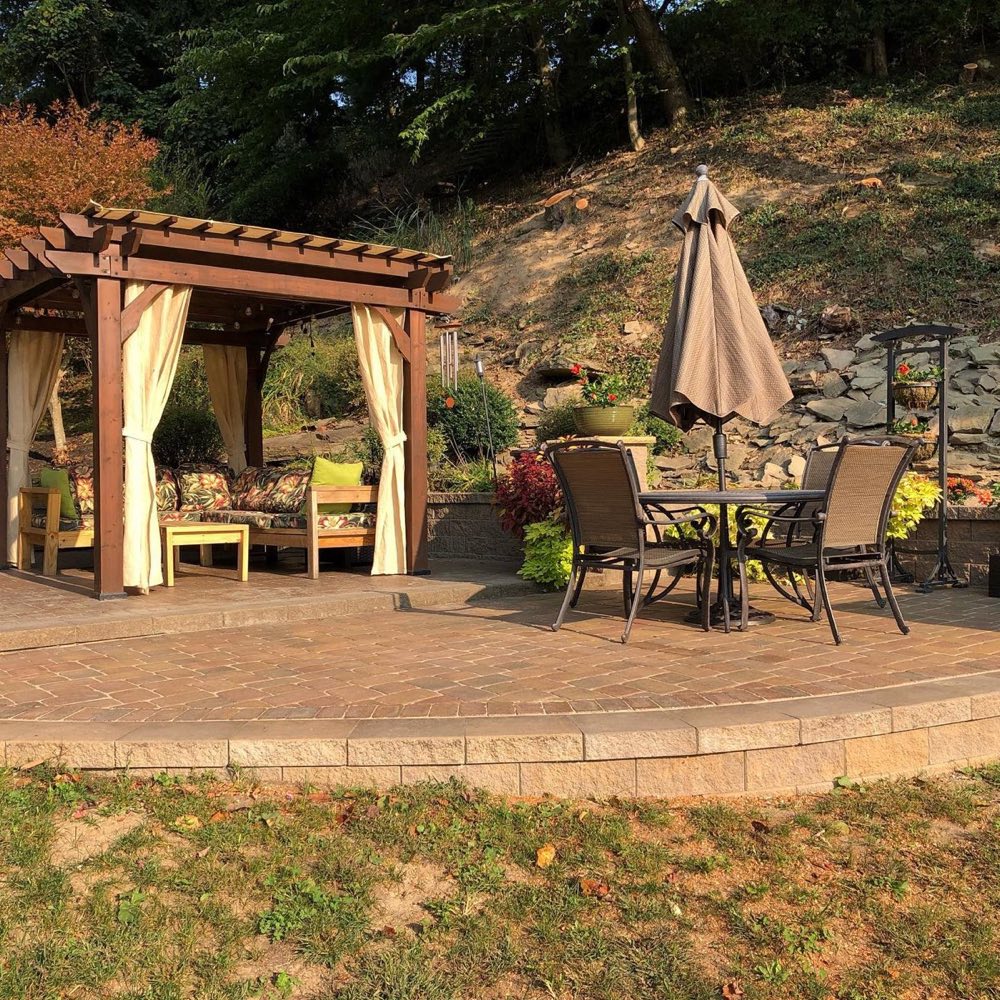Raised Unilock paver patio with pergola seating area and outdoor dining set